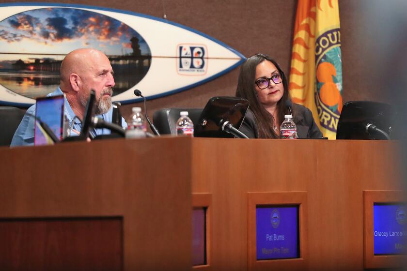 Mayor pro-tem Pat Burns and Mayor Gracey Larrera Van Der Mark listen to public comments as speakers make emotional statements from the podium during vocal Huntington Beach City Council meeting on Tuesday.