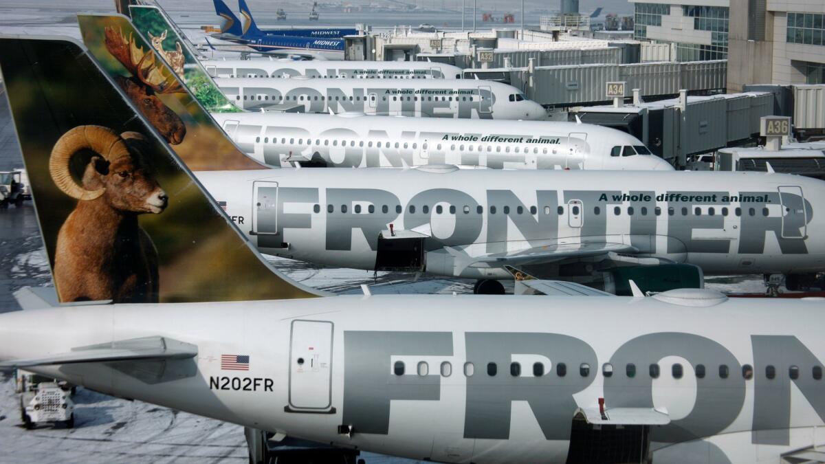 Frontier Airlines jets sit stacked up at gates at Denver International Airport.