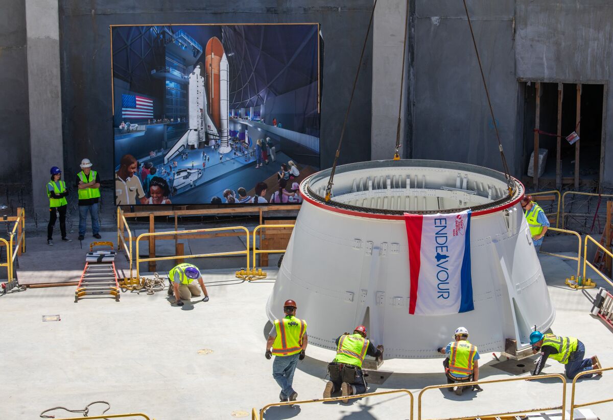 Workers place a solid rocket booster aft skirt onto a seismic isolator pad