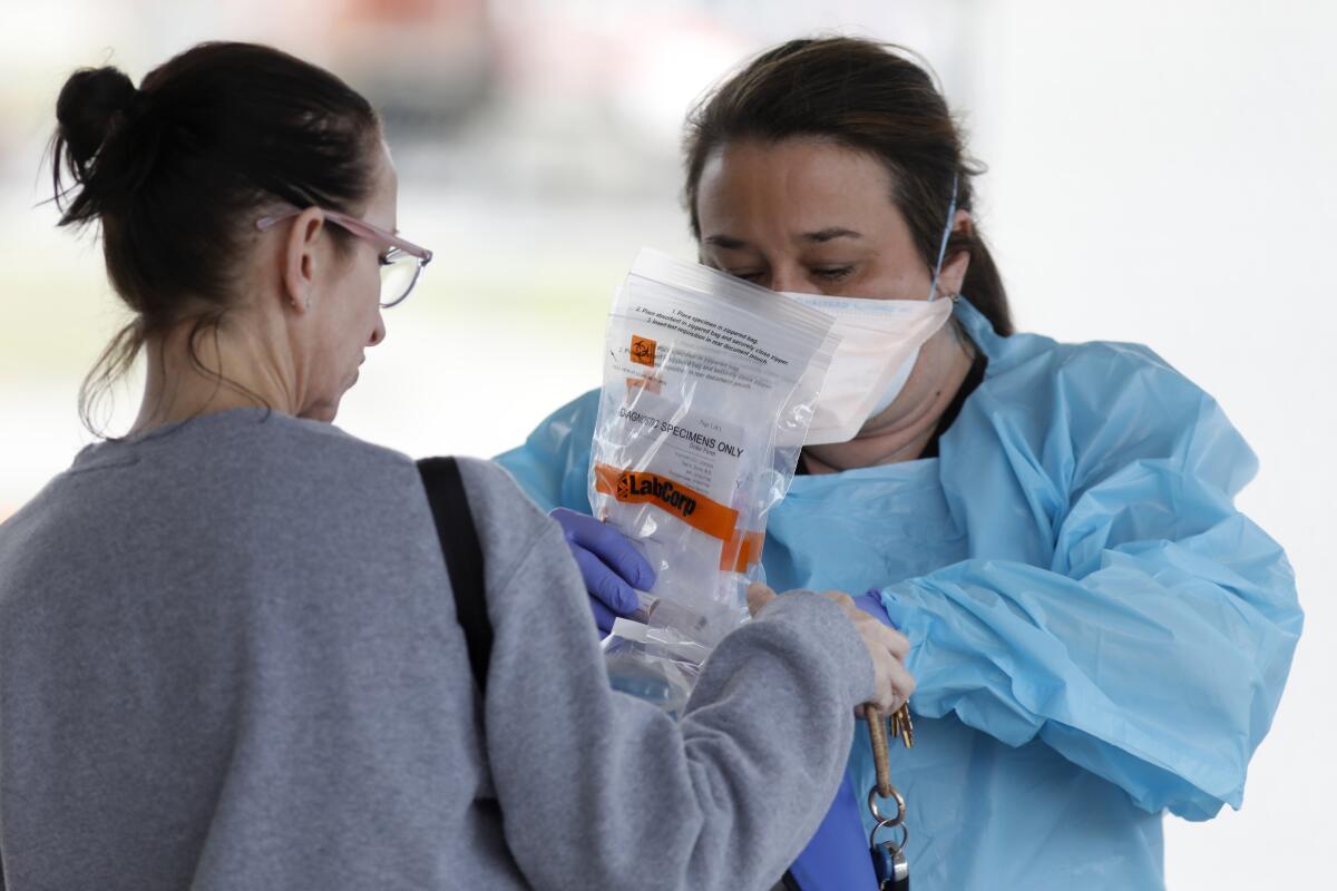 A hospital employee gives specimen collection kits to a lab worker