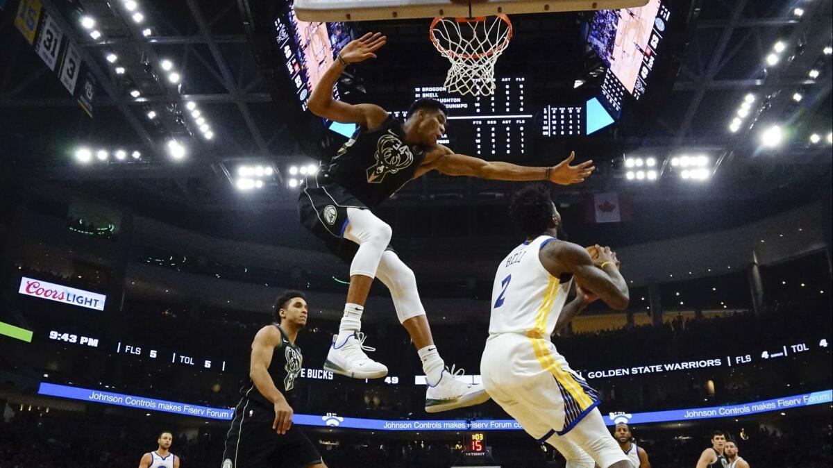 Golden State Warriors forward Jordan Bell is harassed by Milwaukee Bucks forward Giannis Antetokounmpo on Friday night at Fiserv Forum in Milwaukee.