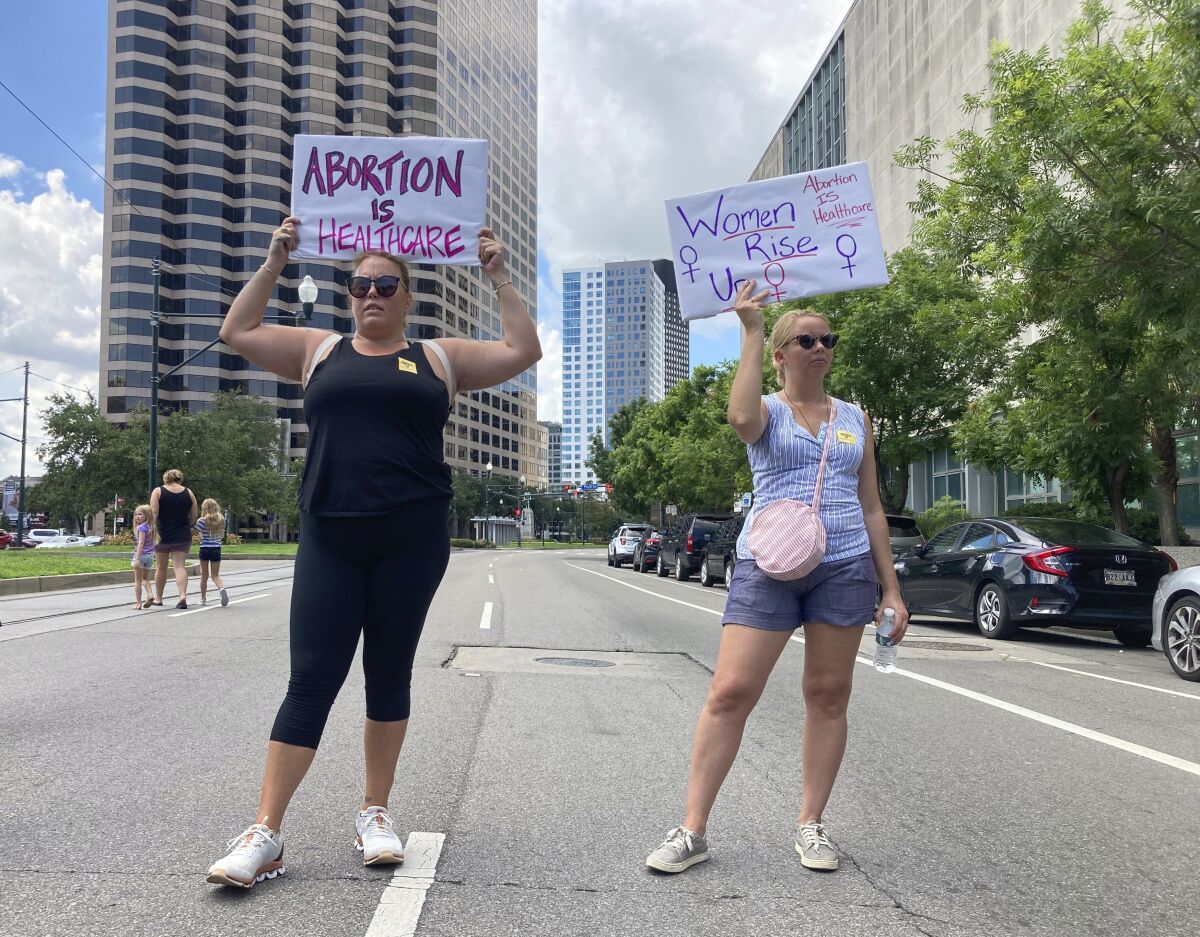 Protesters wave signs and demonstrate in support of abortion access in front of a New Orleans courthouse Friday July 8, 2022. Inside the courthouse a judge was hearing arguments on the state's trigger law designed to outlaw almost all abortions. (AP Photo/Rebecca Santana)