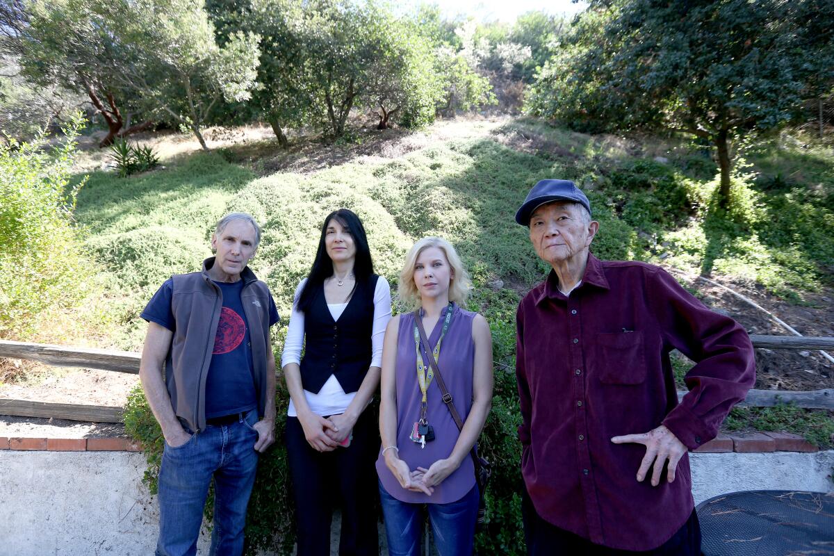 Local residents, from left, Steve Newsom, Lia Lee, Allison Kidd and Lien Yang in the backyard of Newsom's home, which abuts a steep hillside in the Angeles National Forest, in La Cañada Flintridge on Tuesday, Oct. 8, 2019. Residents of the area are trying to help a fawn seen on Sept. 20 with an illegal conibear trap on its hind leg.