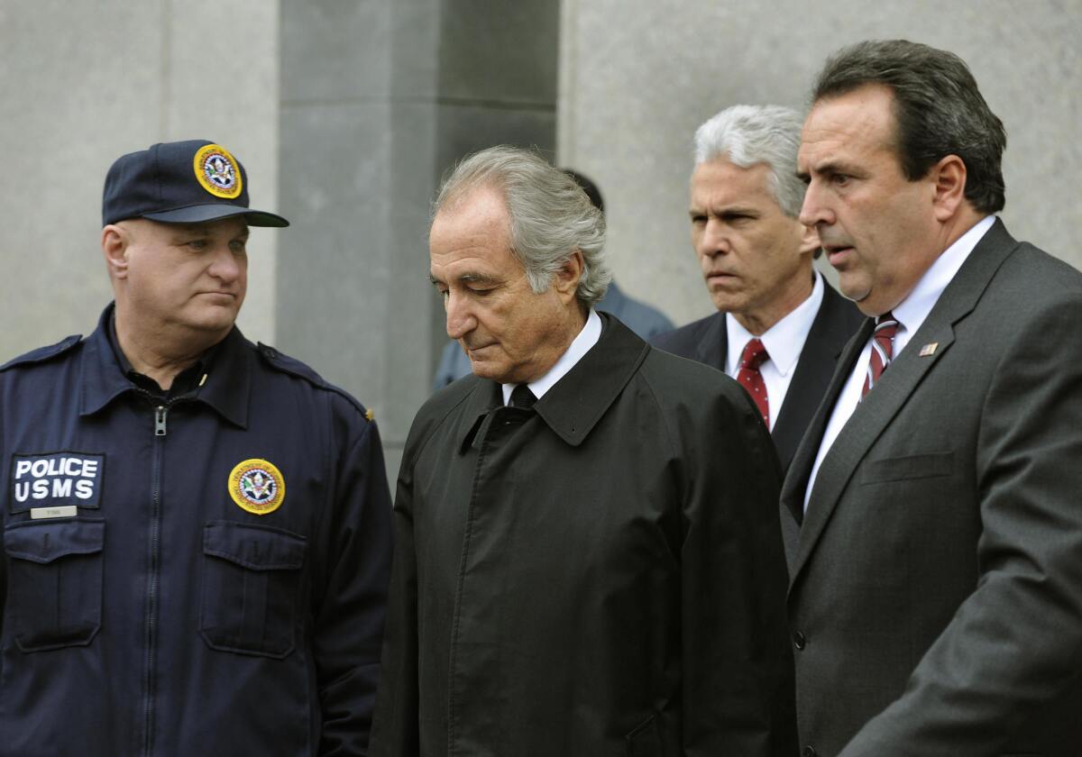 The estate of a Beverly Hills money manger who funneled his clients' money to disgraced investor Bernie Madoff, center, has agreed to pay restitution to victims.