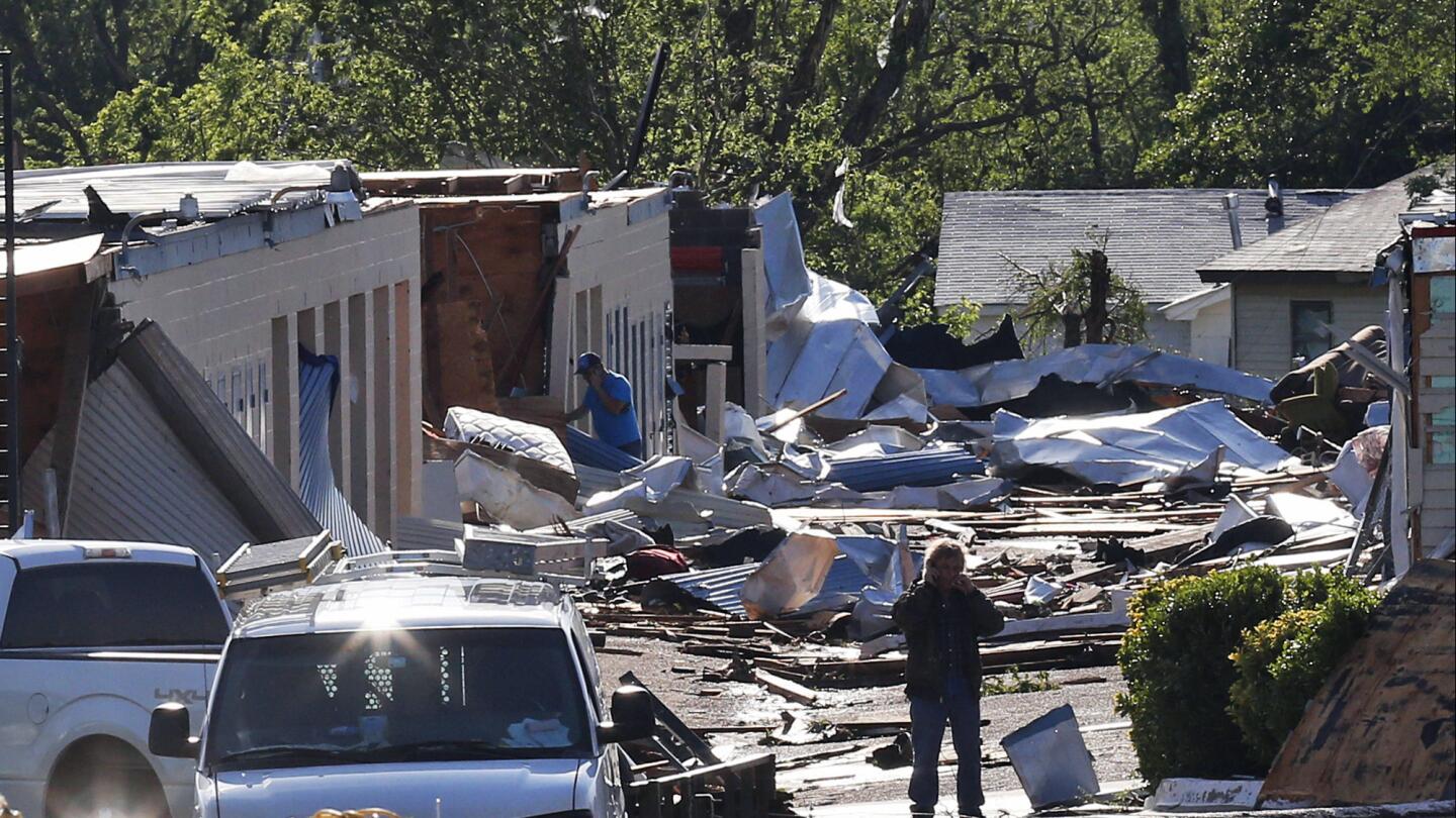 People look through rubble Thursday in an area damaged by severe weather a day earlier.