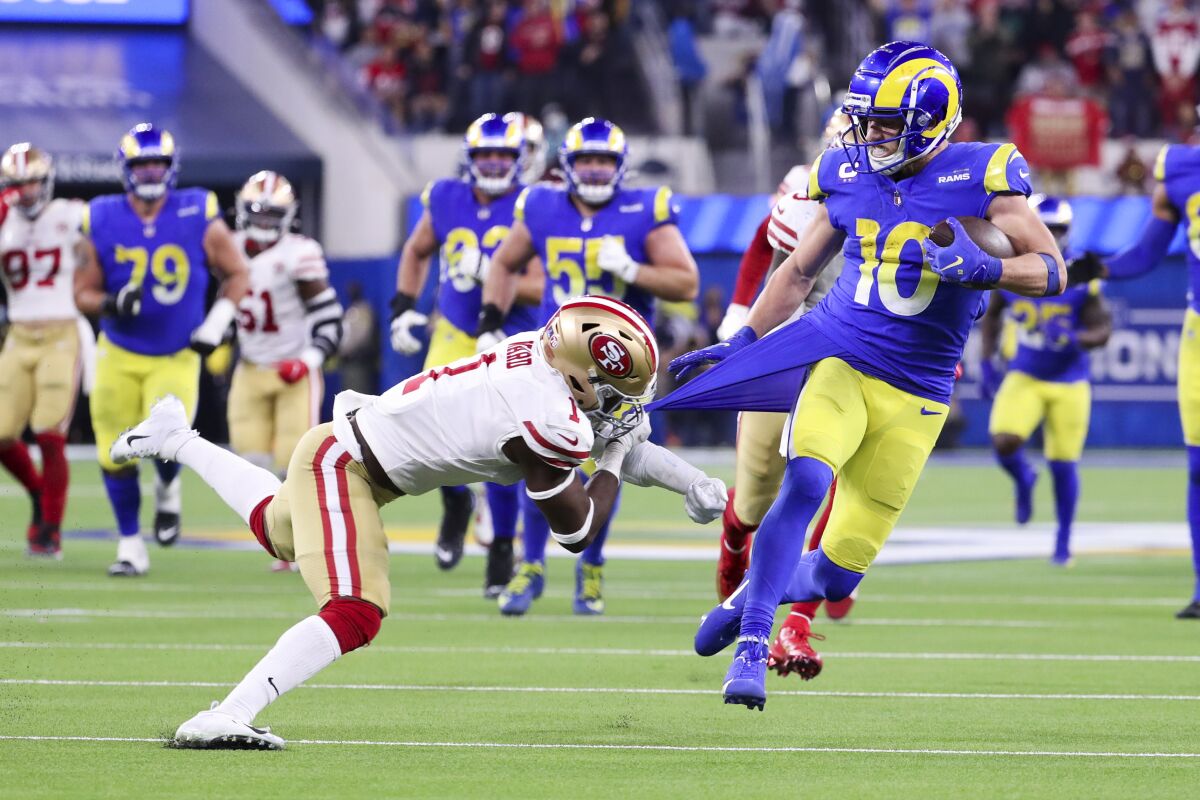 San Francisco's Jimmie Ward  grabs the jersey of the Rams' Cooper Kupp, who runs through the secondary after a catch.