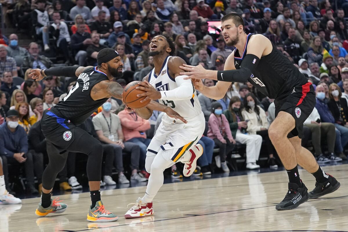 Utah Jazz guard Donovan Mitchell tries to drive between the Clippers' Marcus Morris Sr. and Ivica Zubac.