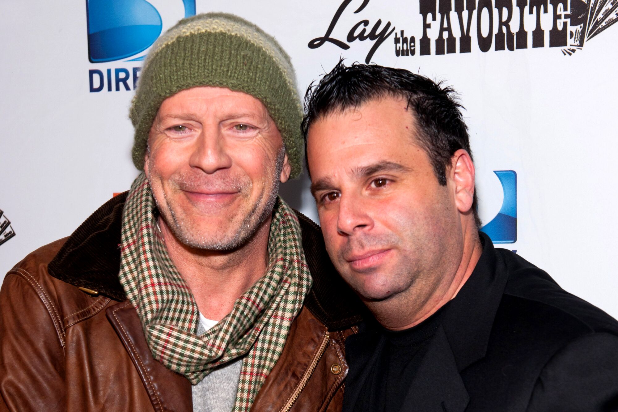 Bruce Willis and Randall Emmett before a backdrop that says DirecTV