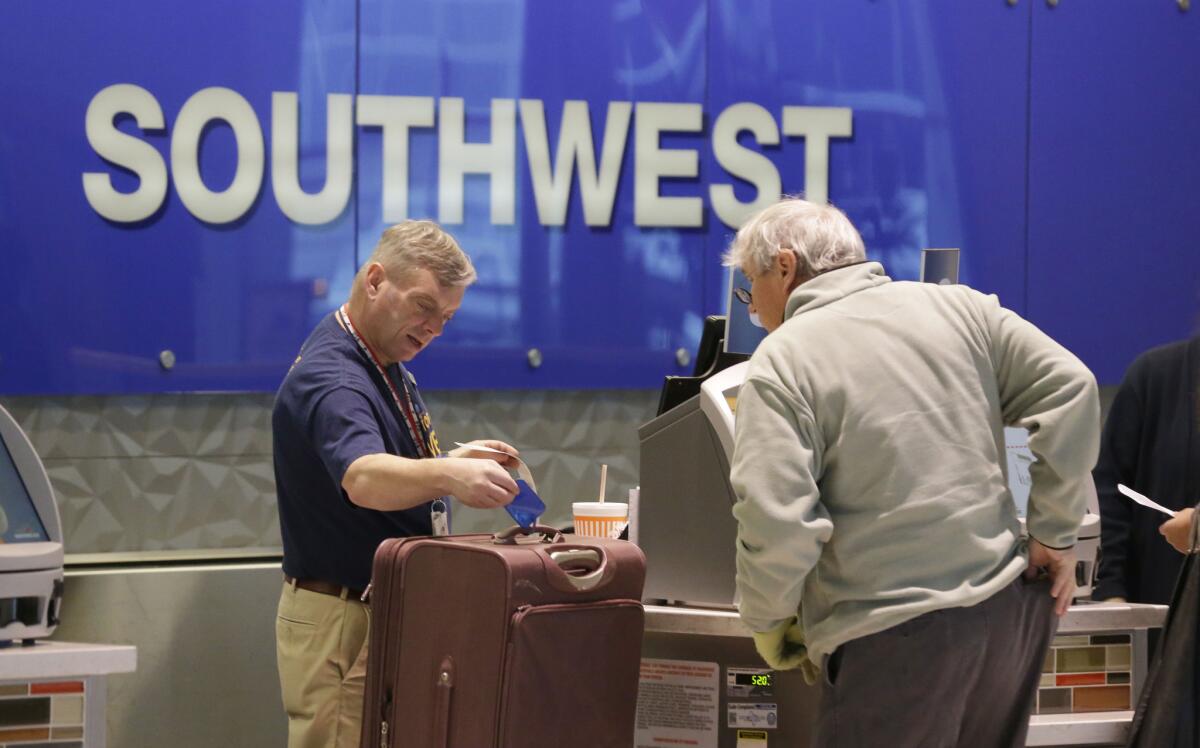 A passenger checks in luggage at the Southwest Airlines counter at Love Field in Dallas. A study by Expedia predicts that air fares to the most popular destinations will drop in 2015.