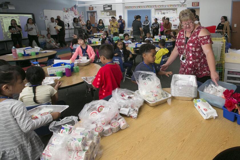 Kindergarten teacher Jennifer Smart, right, helps here students get settled in class and helps them get some breakfast on August 25th, the first day of class at Zamorano Elementary School in the Bay Terrace community of San Diego.