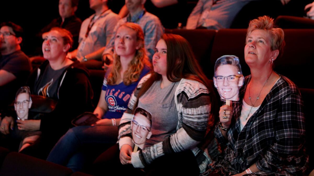 Janice Davern, right, along with other family members, all holding photographs of her grandson, T.J. Bjorklund, a member of the "League of Legends" team from the University of Illinois, watch a championship match against the University of Maryland.