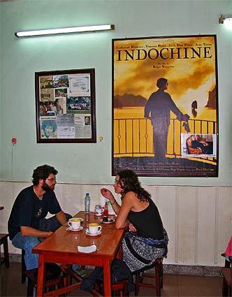 At a cafe in modern-day Hanoi, patrons relax near a large poster for the film.