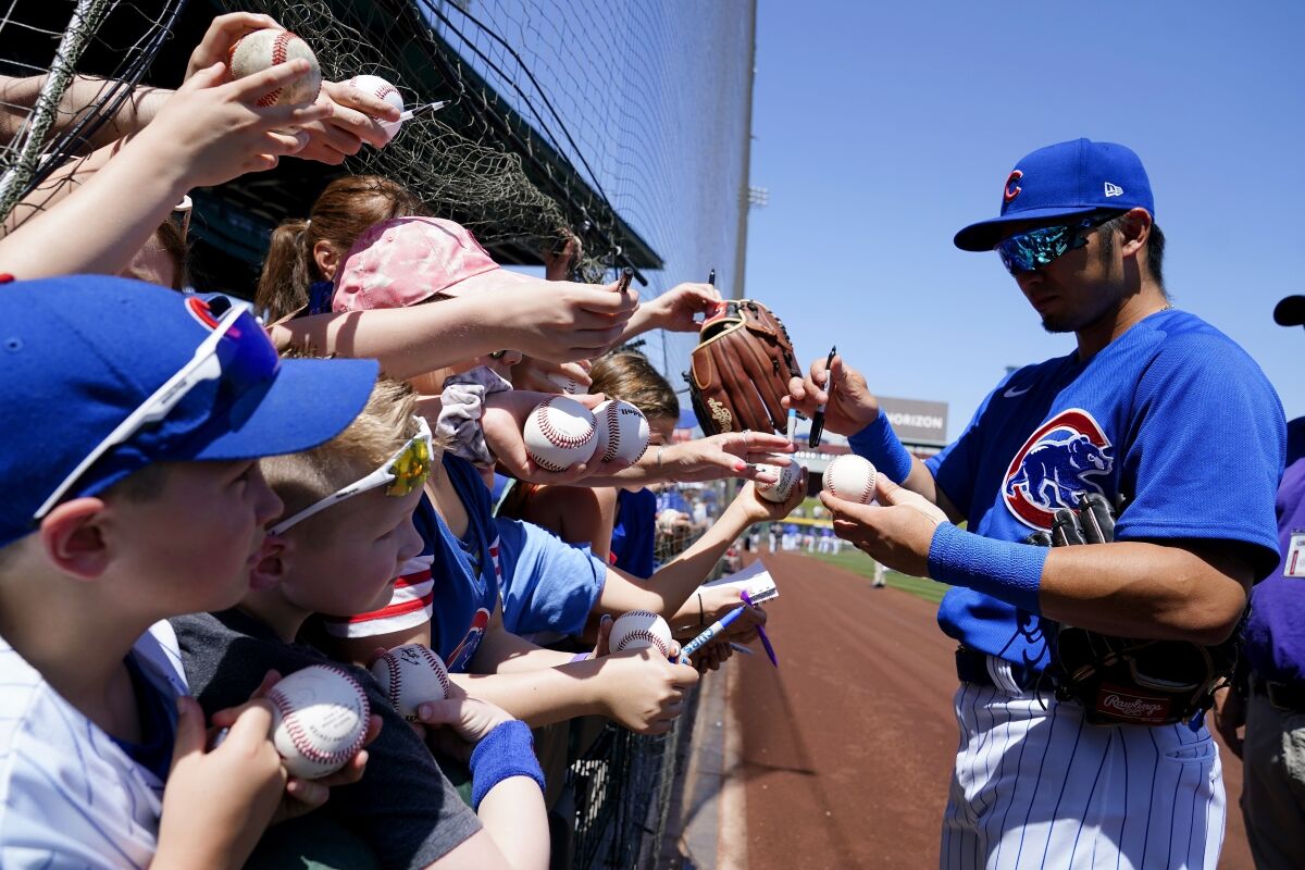 FILE - Chicago Cubs' Seiya Suzuki, of Japan, signs autographs for fans prior to a spring training baseball game against the Chicago White Sox, Monday, April 4, 2022, in Mesa, Ariz. About 1 in 4 fans of Major League Baseball feel at least some anger toward the sport after its first work stoppage in a generation, according to a new poll, but the vast majority are still excited about the new season. Only 27% of Americans say they are currently a fan of MLB, according to the poll from The Associated Press-NORC Center for Public Affairs Research.(AP Photo/Ross D. Franklin, File)