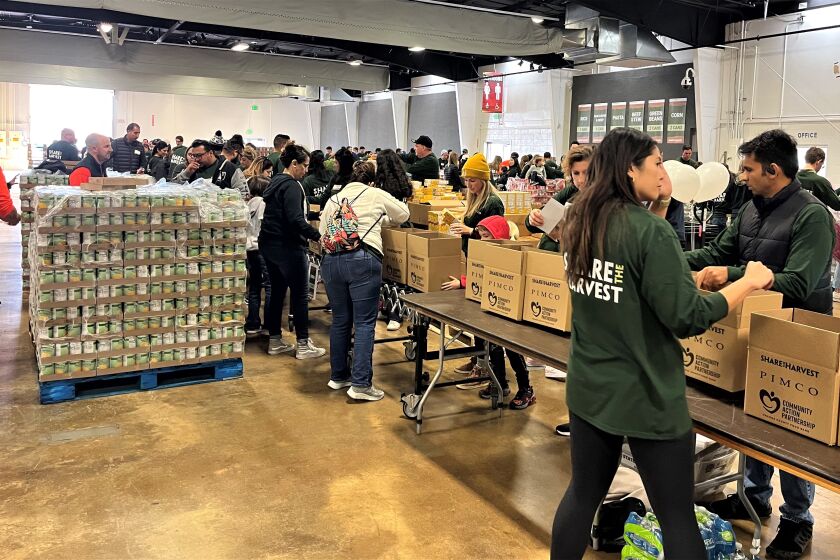 Employees of Newport Beach-based PIMCO at the O.C. fairgrounds Saturday package 15,000 boxes of food and items for families.