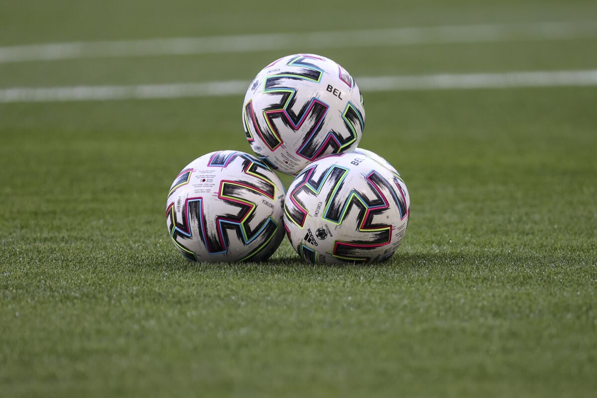 Soccer balls are stacked on the pitch.