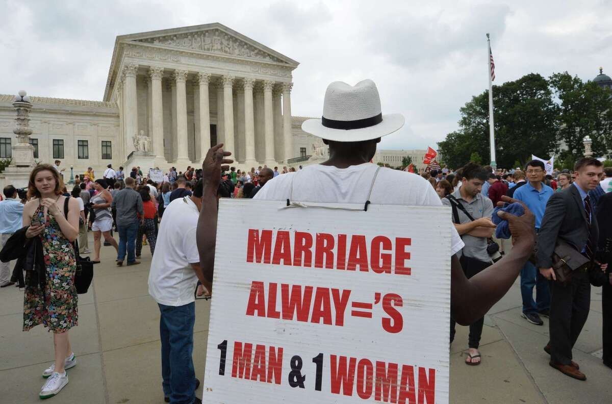 A man carries a protest poster outside the Supreme Court after the justices' historic decision on same-sex marriage was announced Friday.