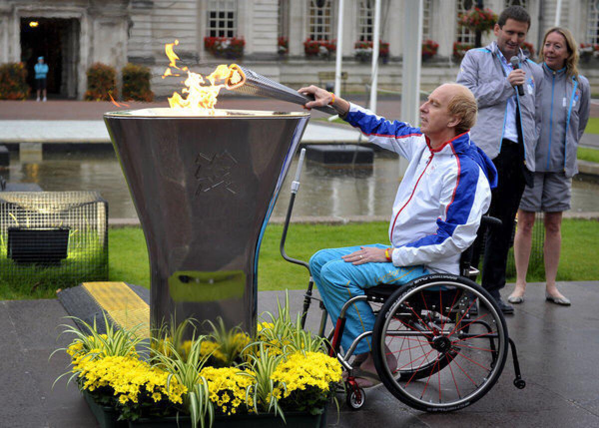 Torchbearer Simon Richardson lights the Paralympics caldron outside City Hall in Cardiff, Wales, on Monday.