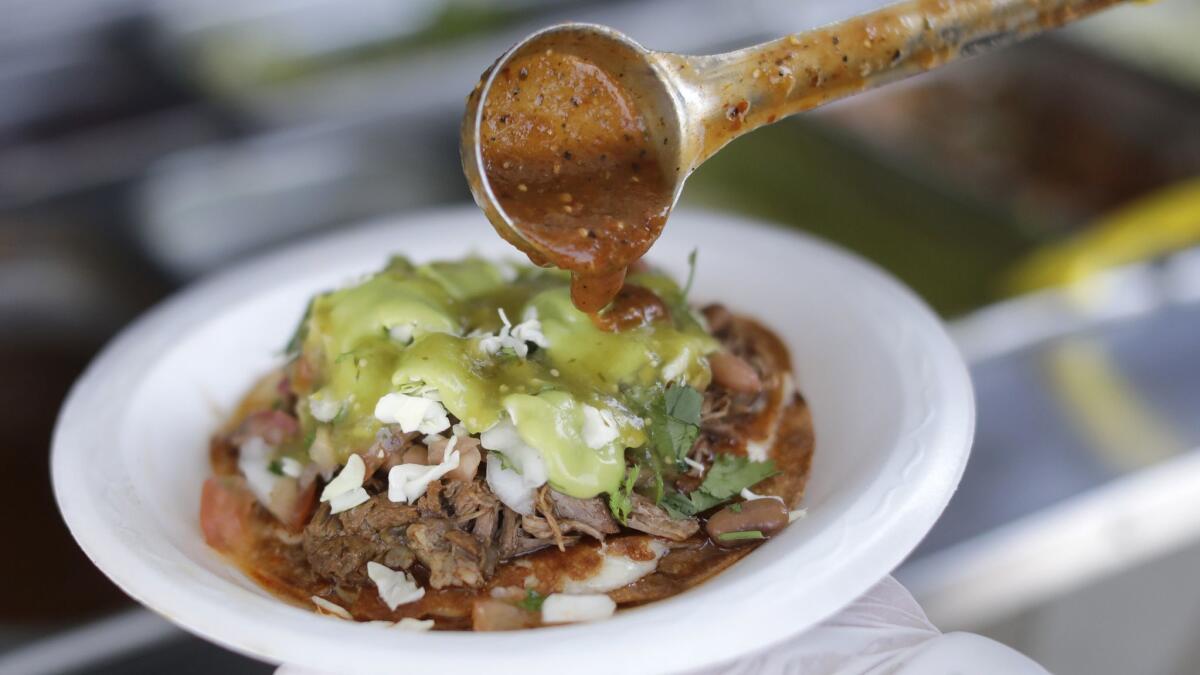 A barbacoa vampiro gets toppings at the family-owned taco truck, Asadero Chikali, in East Los Angeles.