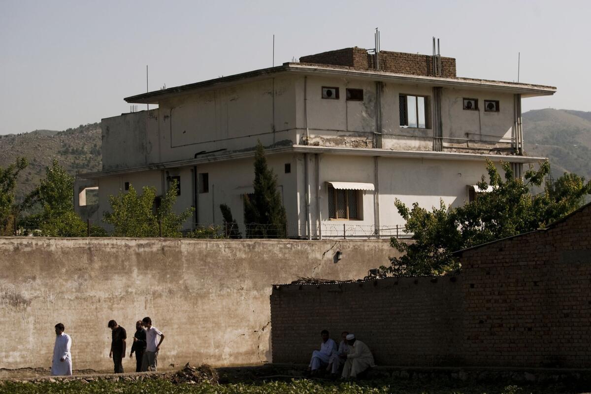 People walk past Osama Bin Laden's compound in Abottabad, Pakistan, where he was killed during a raid by U.S. special forces in May 2011.