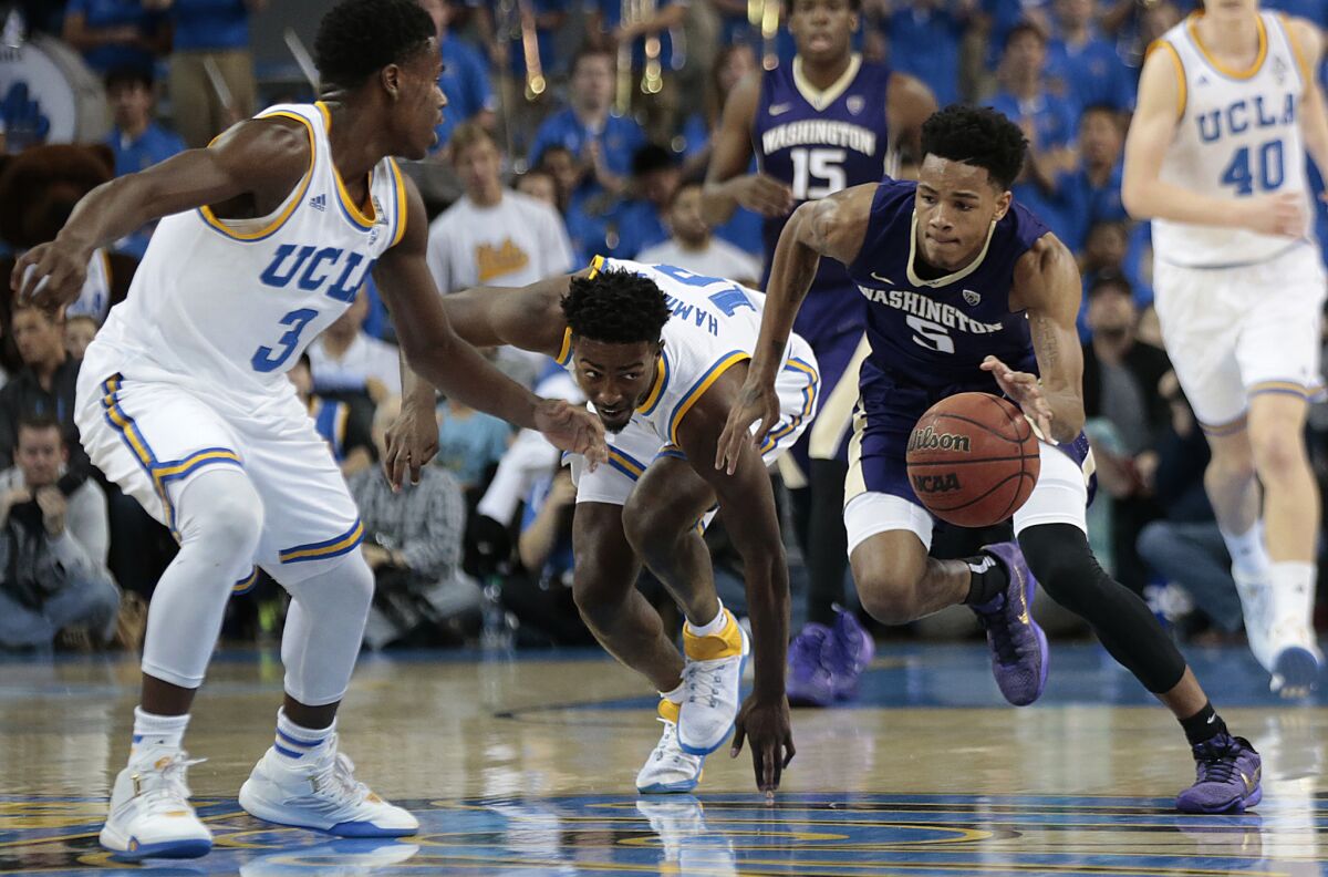 Washington guard Dejounte Murray, right, steals the ball from UCLA guard Isaac Hamilton, center, during first half action at Pauley Pavilion on Thursday.