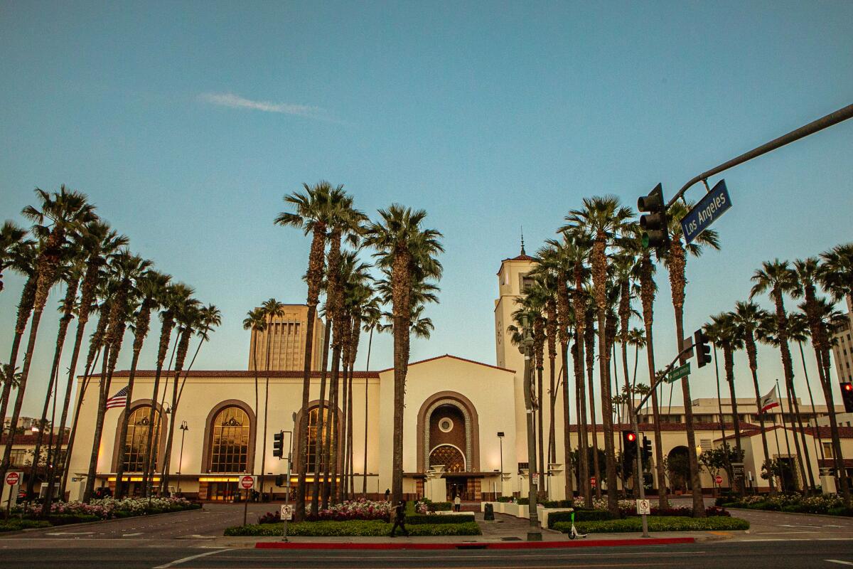 Union Station at dusk with palm trees in front of it.