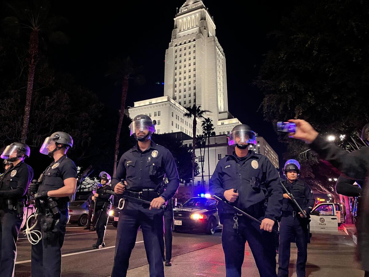 A group of Los Angeles police officers wearing riot helmets and holding batons in downtown Los Angeles