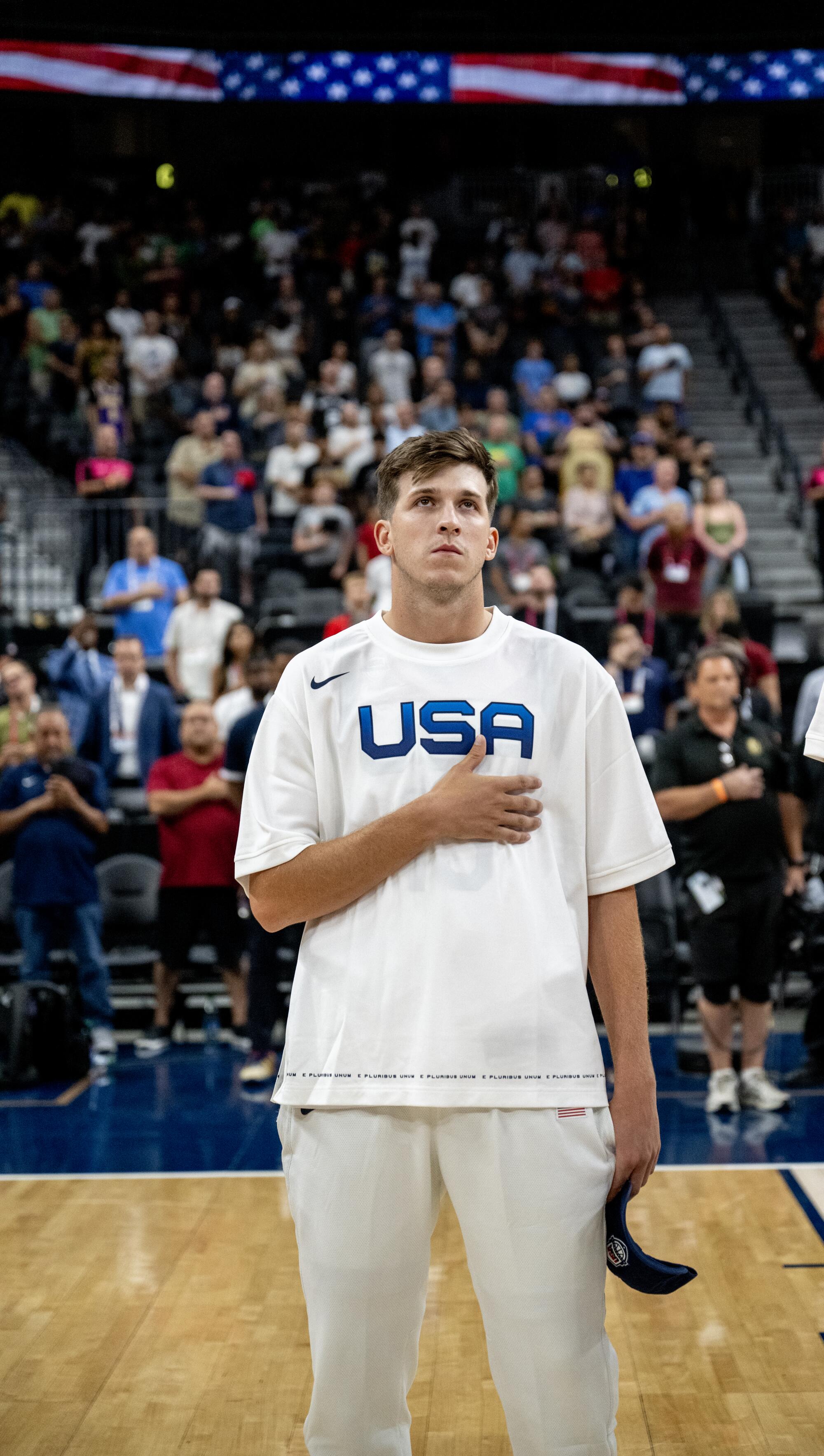 Team USA's Austin Reaves puts his hand over his heart during the singing of the national anthem before an exhibition game.
