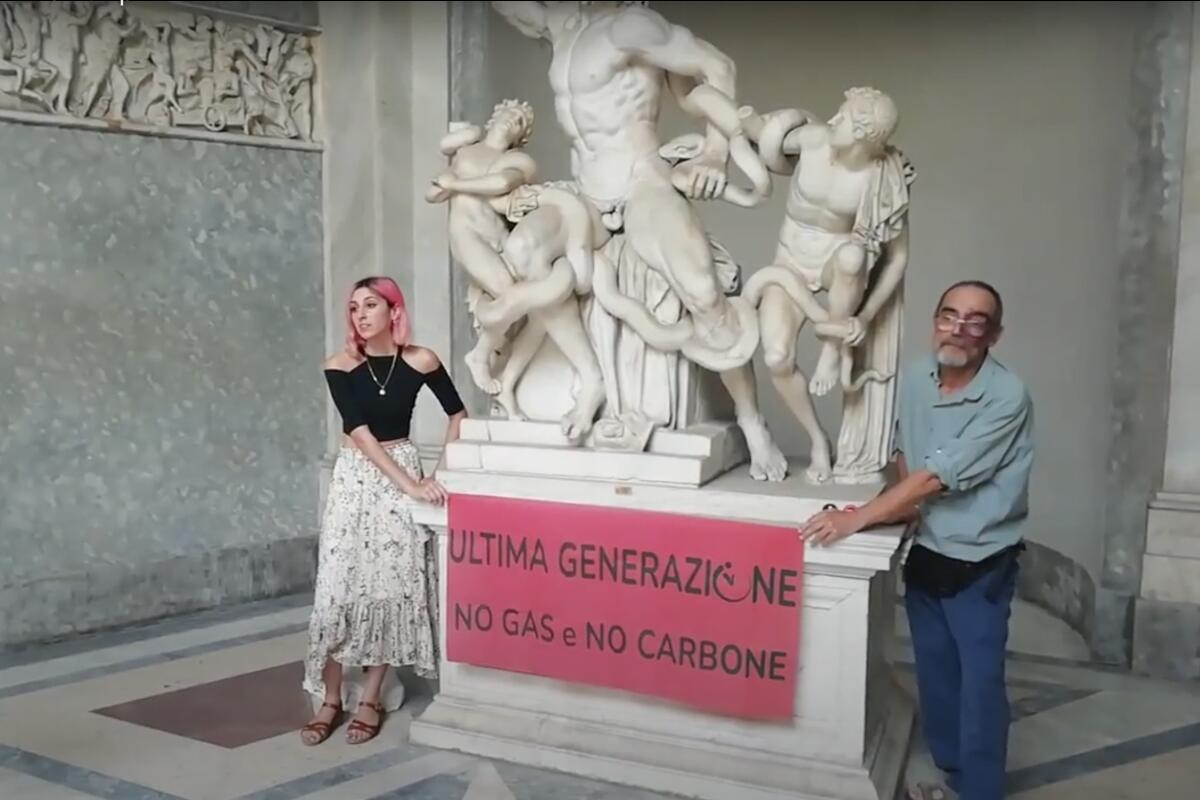 A video grab from a footage made available by environmental activists, shows two members of Ultima Generazione, or Last Generation in English, glued their hands on the Roman statue of Laocoön and His Sons, one of the masterpieces of the Vatican Museums collection, to protest against climate change, Thursday, Aug. 18, 2022. The activists displayed a banner reading, "Last Generation No Gas No Coal" urging politicians to listen to the call from the scientific community and act against climate change. (Ultima Generazione Via AP)