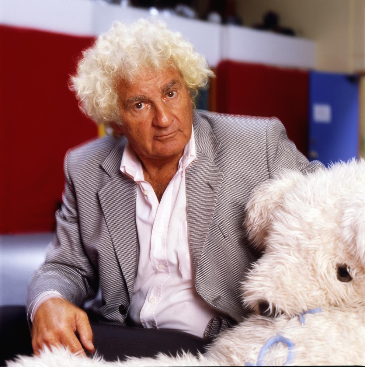 Arthur Janov in a suit next to a stuffed animal. 