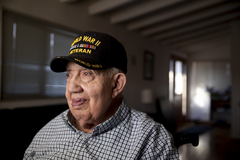 A man wears a World War II veteran cap.