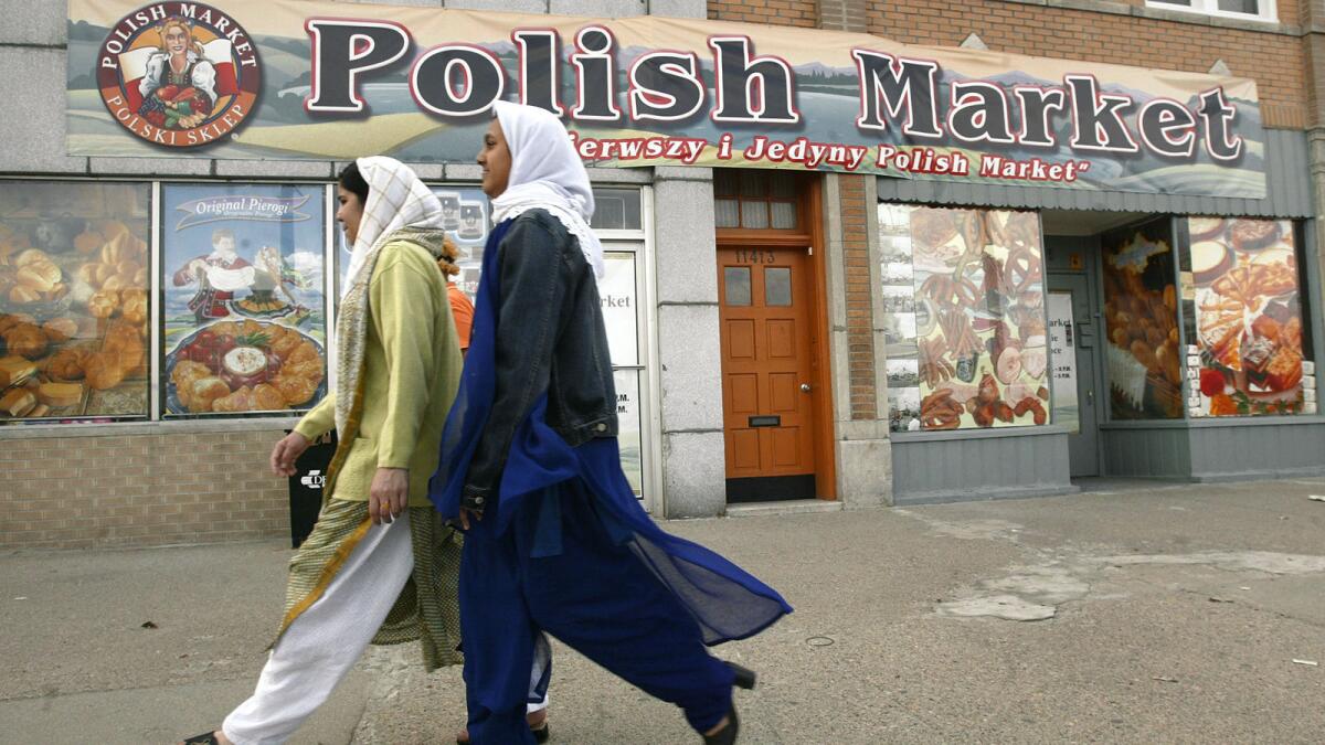 Muslim women walk past a Polish Market in Hamtramck, Mich.