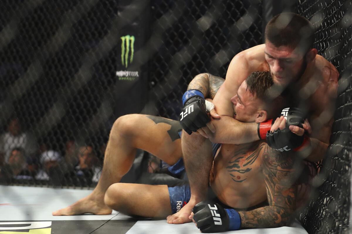 Russian UFC fighter Khabib Nurmagomedov, choke holds UFC fighter Dustin Poirier, of Lafayette, La., during Lightweight title mixed martial arts bout at UFC 242, in Yas Mall in Abu Dhabi, United Arab Emirates, Saturday , Sept.7 2019. (AP Photo/ Mahmoud Khaled)