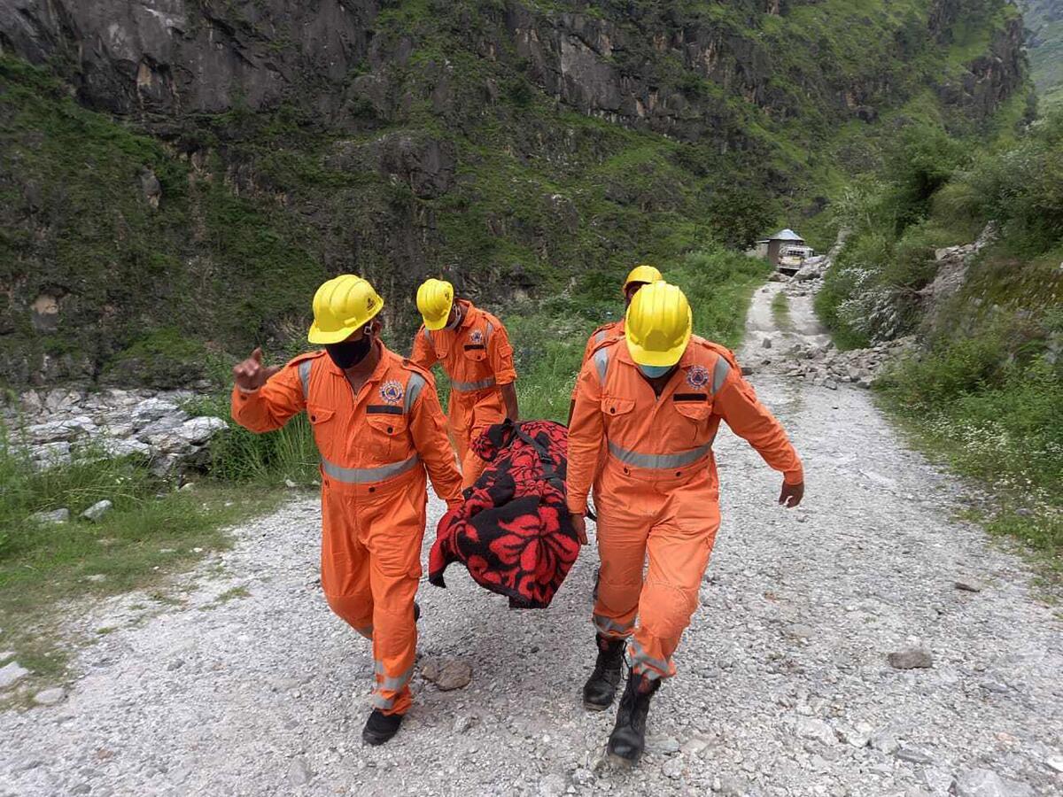 This photograph provided by India's National Disaster Response Force (NDRF) shows NDRF soldiers carrying the body of a victim from the site of a landslide in Kinnaur district in the northern Indian state of Himachal Pradesh, Wednesday, Aug. 11, 2021. A landslide struck several vehicles traveling on a highway in the hills of northern India on Wednesday, trapping as many as 50 people, officials said. (National Disaster Response Force via AP)