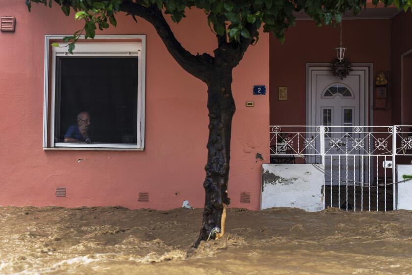 Apostolis Dafereras, 83, looks out of the window of his house into the flooded street in Volos city, Greece, Thursday, Sept. 28, 2023. Torrential rainfall has caused widespread flooding in and around the Greek city of Volos and other central areas of the country for the second time in less than a month. (AP Photo/Petros Giannakouris)