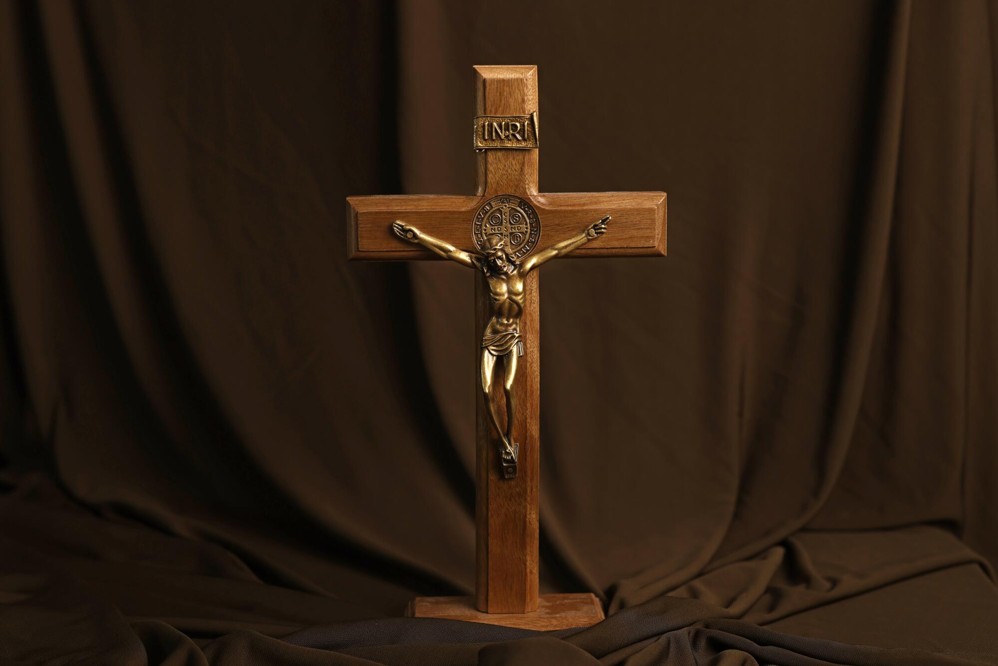 A wooden crucifix on a brown sheet used as a backdrop
