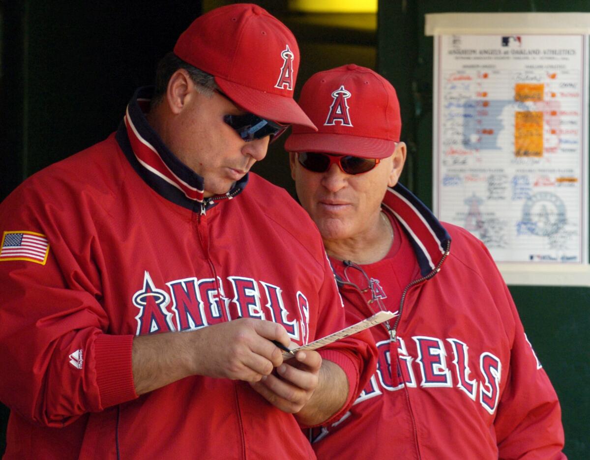 Angels manager Mike Scioscia, left, and bench coach Joe Maddon look over a lineup card on Oct. 3, 2004.