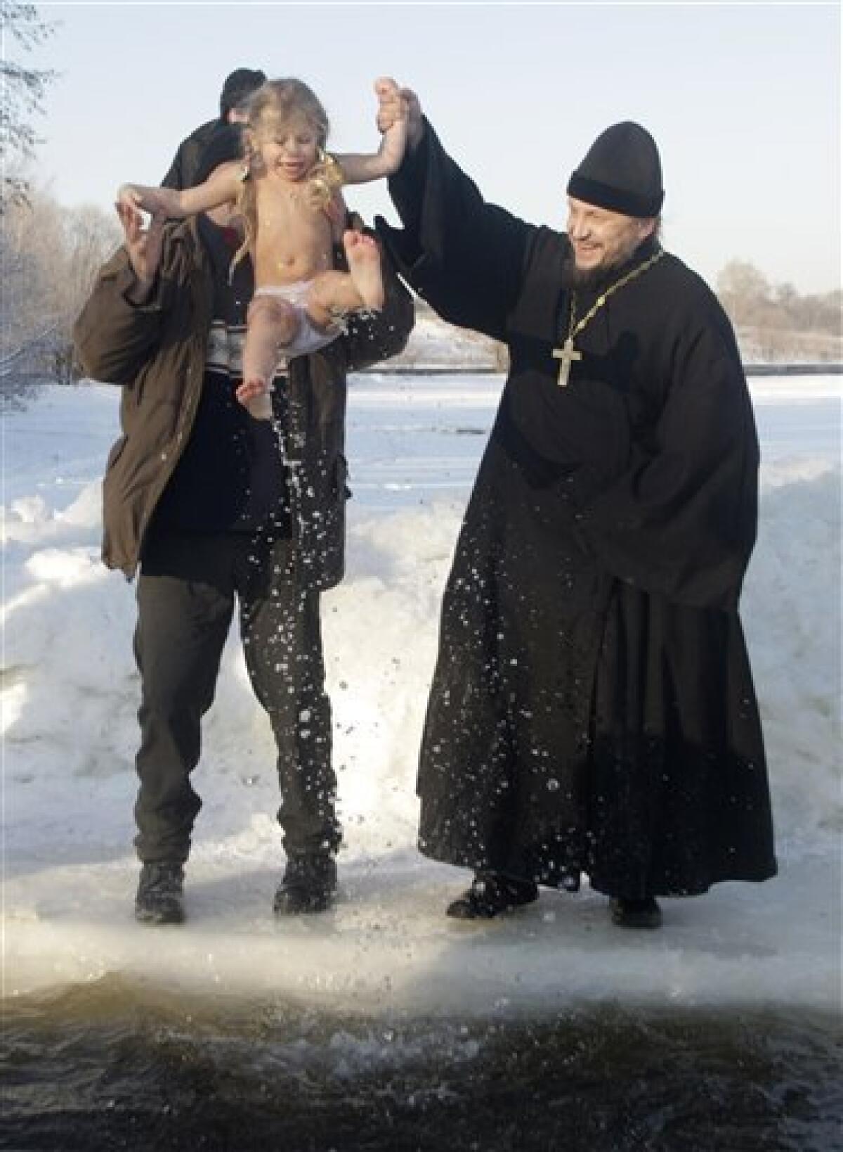 Russian Orthodox priest, right, and believer help a girl to get out of ice cold water after plunging into icy pond to mark the upcoming Epiphany in the northwestern Moscow, Monday, Jan. 18, 2010. Thousands of Russian Orthodox Church followers plunged Monday into icy rivers and ponds across the country to mark the upcoming Epiphany, cleansing themselves with water deemed holy for the day. Water that is blessed by a cleric on Epiphany is considered holy and pure until next year's celebration, and is believed to have special powers of protection and healing. The Russian Orthodox Church follows the old Julian calendar, according to which Epiphany falls on Jan. 19. Moscow temperatures on Monday morning dropped to -20 Celsius (-4 Farenheit). (AP Photo/Mikhail Metzel) — AP