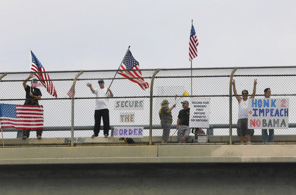Protesters wave to motorists on the Wardlow Road overpass of the 605 Freeway in Long Beach on Saturday.
