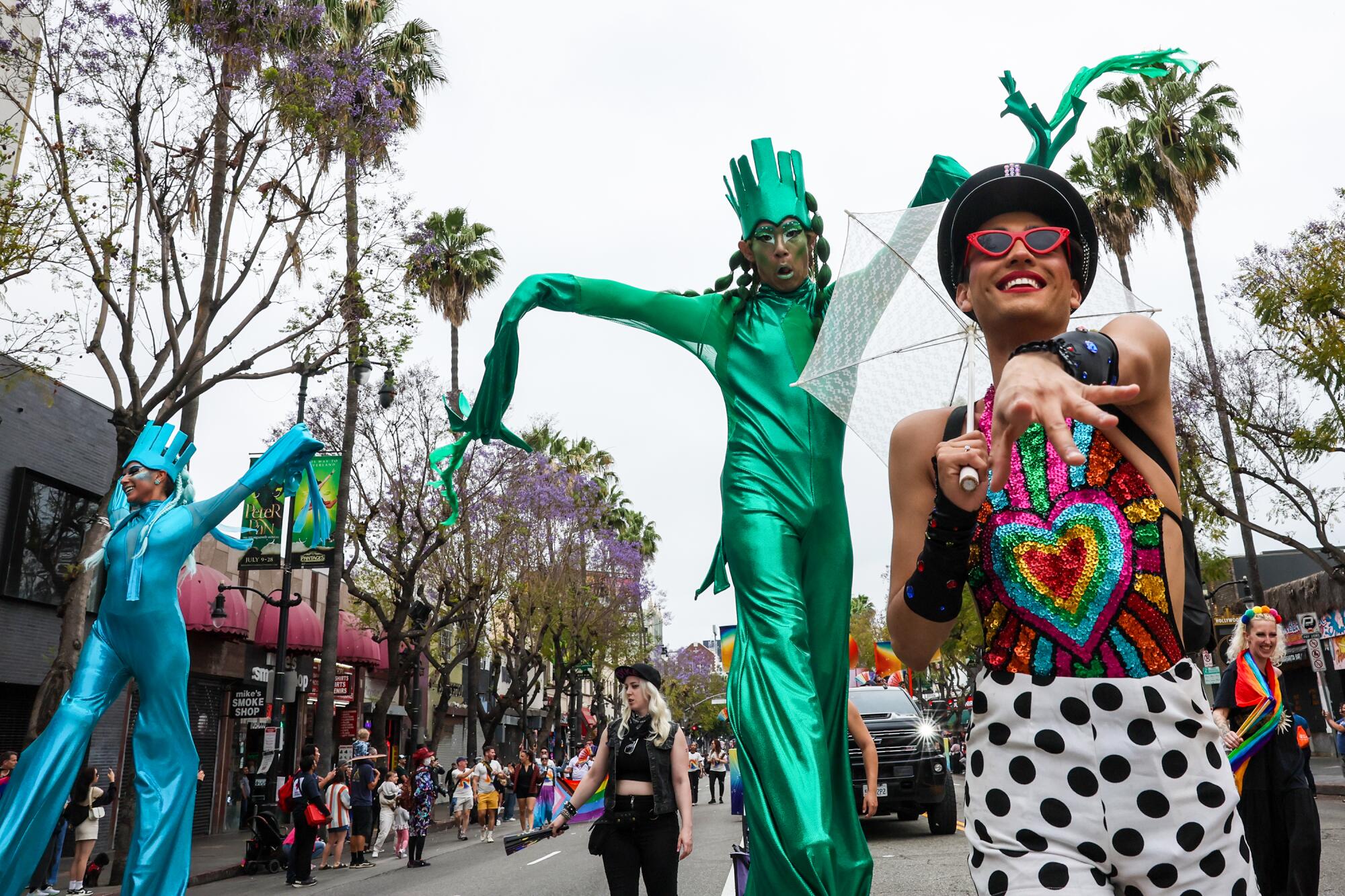 Tino Glamour leads a group of stilted dancers in brightly colored outfits in the 2024 LA Pride Parade.