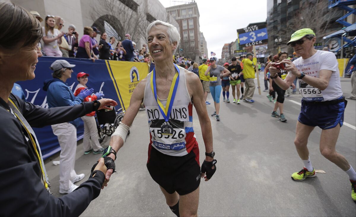 FILE - In this April 17, 2017, file photo, three-time Boston Marathon winner Uta Pipping, left, congratulates Ben Beach, of Bethesda, Md., after he finished running his 50th consecutive Boston Marathon in Boston. Ben Beach has experienced a little bit of everything while running in a record 53 consecutive Boston Marathons — from New England’s unpredictable weather to a diagnosis with dystonia to the 2013 bombing to last year’s pandemic disruption. (AP Photo/Elise Amendola, File)