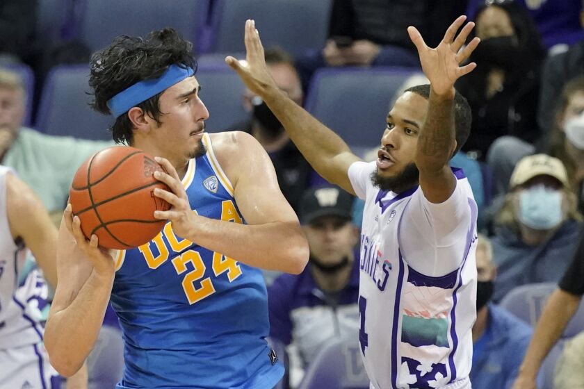 UCLA guard Jaime Jaquez Jr. (24) looks to pass around the defense of Washington guard PJ Fuller, right, during the first half of an NCAA college basketball game, Monday, Feb. 28, 2022, in Seattle. (AP Photo/Ted S. Warren)