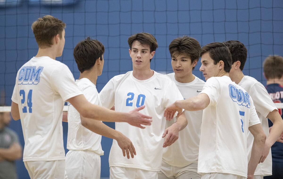 Corona del Mar teammates celebrate with Adam Flood (20) after he put a ball away in a nonleague match against Beckman on Feb. 21.