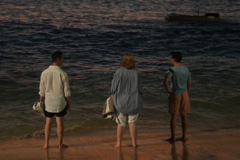 Three adult siblings on the beach, looking out at the ocean