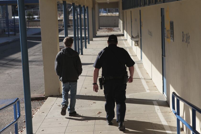 FILE - In this Dec. 9, 2013, file photo, a school resource officer in Anderson, Calif., walks a middle school student back to class. Portland Public Schools, Oregon's largest school district, will discontinue its use of Portland Police Bureau school resource officers. Superintendent Guadalupe Guerrero said Thursday, June 4, 2020, the district needed to "re-examine our relationship" with the police in light of the nationwide upheaval over the death of George Floyd. (Andreas Fuhrmann/The Record Searchlight via AP, File)