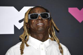 Lil Wayne wears large sunglasses and smiles with his signature locs