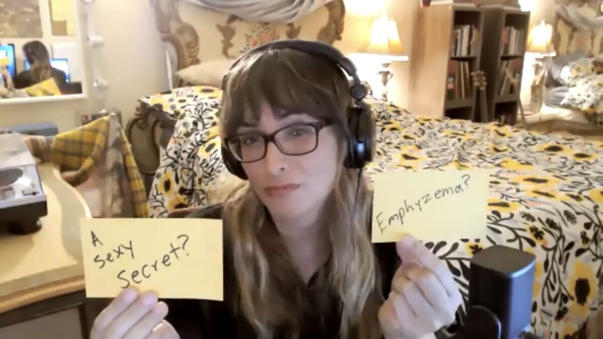 Jeena Bloom, wearing headphones in a bedroom, holds up sticky notes that say "A sexy secret?" and "Emphyzema?"