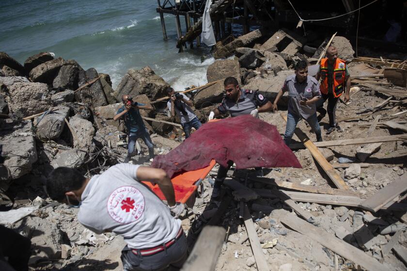 Palestinian rescue workers carry the remains of a man found next to a beachside cafe after it was hit by an Israeli airstrike, in Gaza City, Monday, May 17, 2021. (AP Photo/Khalil Hamra)