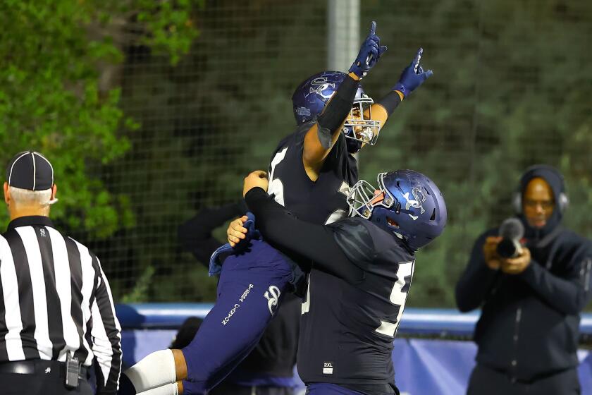 Sierra Canyon High running back Dane Dunn leaps into a teammates arms after scoring a touchdown against Inglewood on Nov. 26.