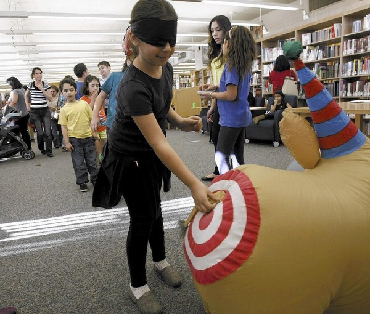 Stacey Torosian, 8, of Glendale, pins the tail on the donkey during the Grandview Library's 50th anniversary celebration at the library on Friday, Jan. 17, 2014.