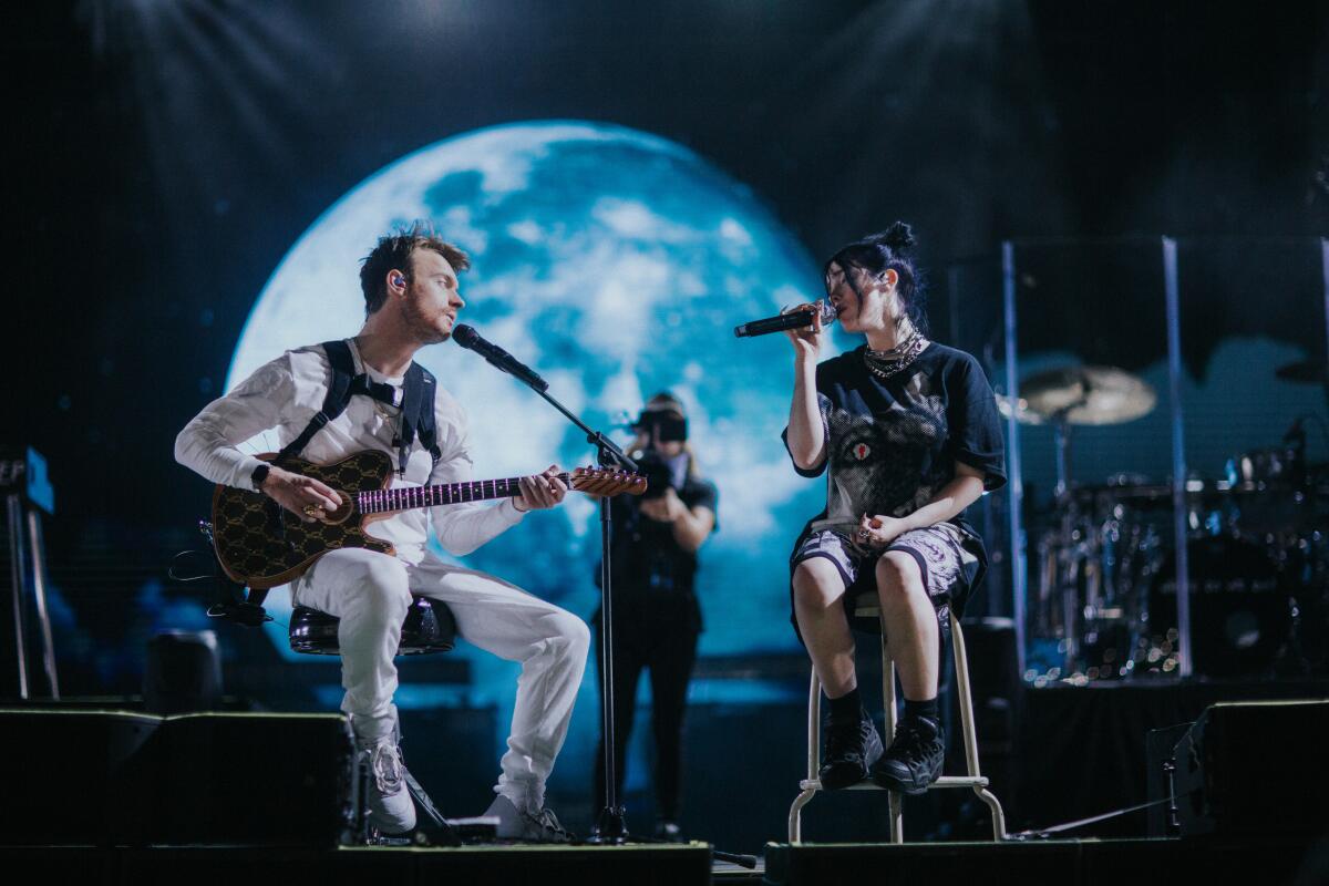 Billie Eilish and Finneas O'Connell on stage in "Billie Eilish: The World's A Little Blurry," now streaming on Apple TV+.